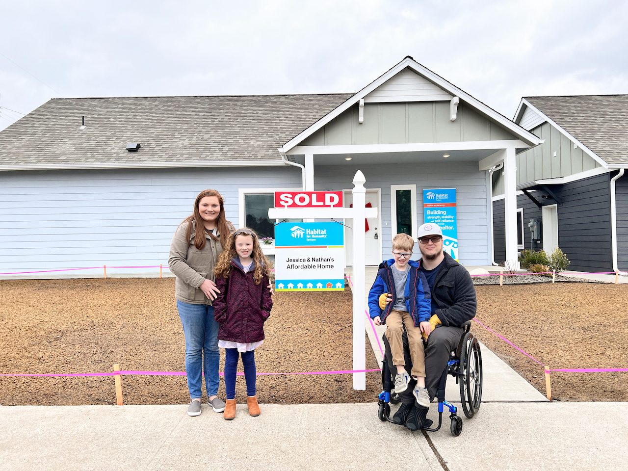 Family in front of Sold Habitat home